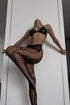 A pair of fishnet stockings with a lace pattern, featuring a bold design with fishnet sides and a hook and eye closure at the thigh.