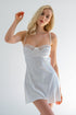 A woman wearing a white satin nightdress with delicate lace trim and adjustable spaghetti straps.